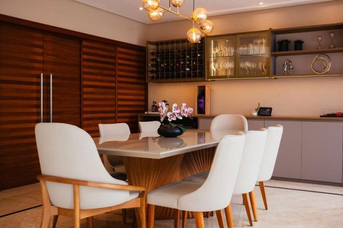 Salle à manger élégante avec table en bois sculptée et chaises blanches, illustrant une salle à manger manque de convivialité malgré un décor luxueux.