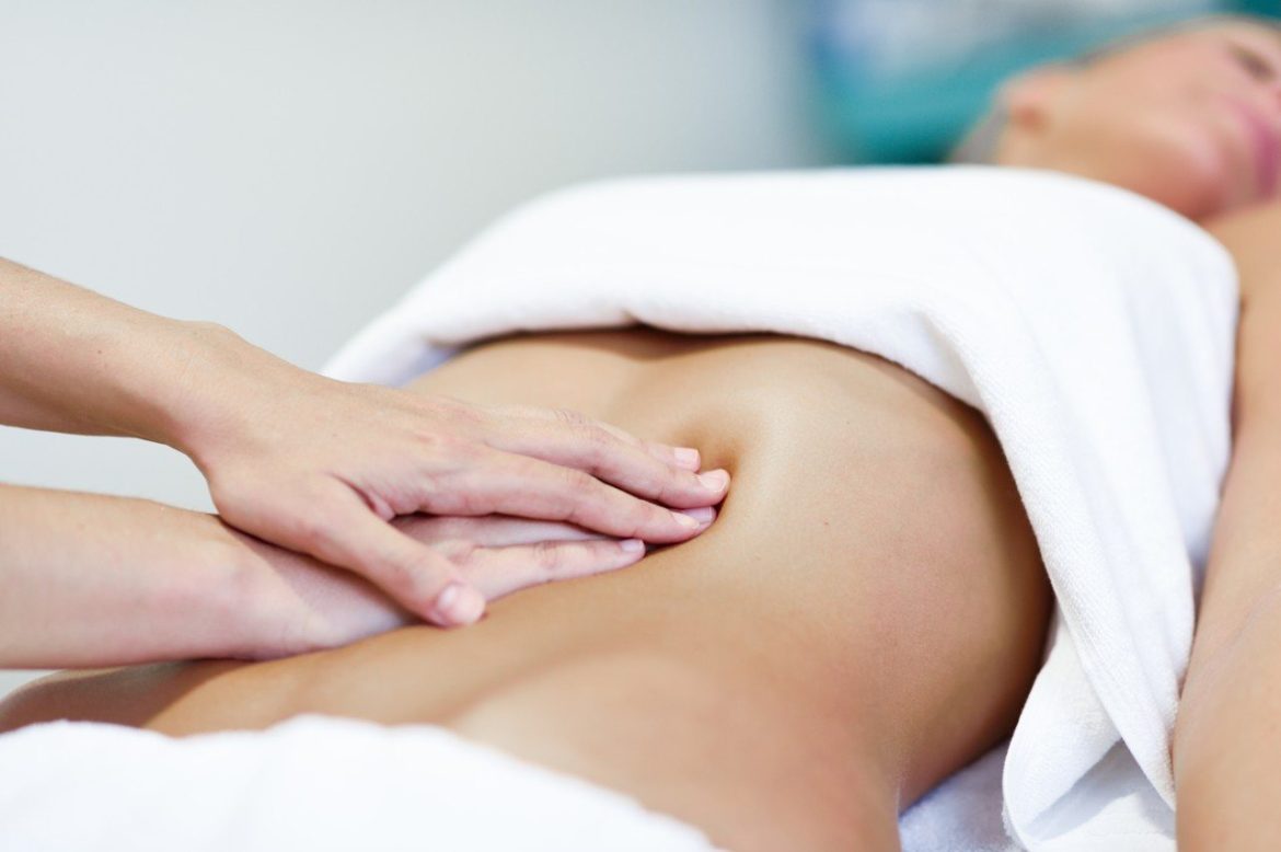 Praticien effectuant un massage abdominal digestion et ballonnement sur le ventre d'une femme allongée.